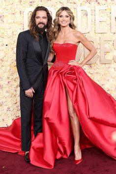 a man and woman in formal wear posing on the red carpet