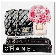 a chanel bottle and flowers are sitting on top of three books, one is black and the other is pink