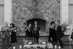 a group of people standing in front of a fire place with candles on the table