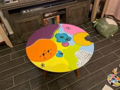 a multicolored table sitting on top of a wooden floor next to a tv