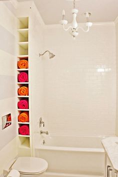 a bathroom with a toilet, bathtub and shelves in the wall that hold towels