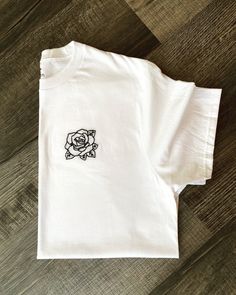 "This listing is for a 100% cotton tee with a hand-embroidered Rose.  Tees are high quality, soft, tagless and 100% cotton.  All tees run true to size. Sizing charts are listed below. Adult Tee Sizing (in inches): *Tees hit at the hip. XS: Chest- 30-32\" // Hip- 33\" S: Chest- 34-36\" // Hip- 34-36\" M: Chest- 38-40\" // Hip- 37-39\" L: Chest- 42-44\" // Hip- 40-42\" XL: Chest- 46-48\" // Hip- 43-44\" XXL: Chest- 50-52\" // Hip- 45-46\" Kids Tee Sizing (in inches): S (6-7): Height- 48-49.5\" // Chest- 26\" M (8): Height- 50-52\" // Chest- 27\" L (10-12): Height- 56-58\" // Chest- 28\" XL (14-16): Height- 61-64\" // Chest- 31\" XXL (18): Height- 65-66\" // Chest- 32\" Care Instructions:  Garment is safe to machine wash, but would recommend a gentle cycle. Tumble dry on low or lay flat to dr Embroidered Rose, Embroidered Roses, Rose Shirts, Rose T Shirt, Stitch Shirt, Embroidered Tee, Kid Tees, Embroidered Shirt, Hand Stitched