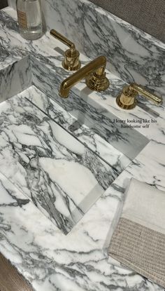 a marble sink with gold faucets and towels