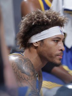 a close up of a person with a headband and tattoos on his chest,