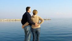 a man and woman standing next to each other by the water