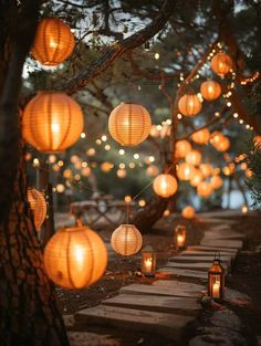 many lanterns are hanging from the trees and lit up by string lights in front of them