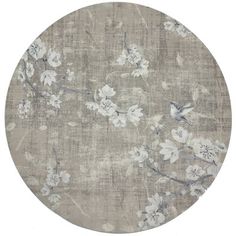 a round rug with white flowers and leaves on the top, in light grey tones