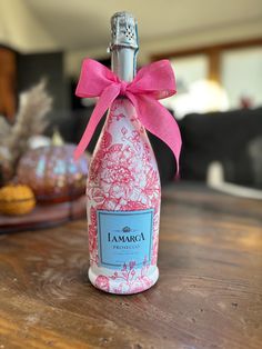 a bottle with a pink bow on it sitting on a table next to some cookies