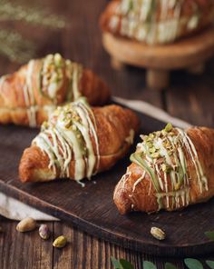 three croissants covered in white icing and sprinkled with pistachio