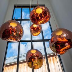 a bunch of lights hanging from a ceiling in front of a window with blue sky