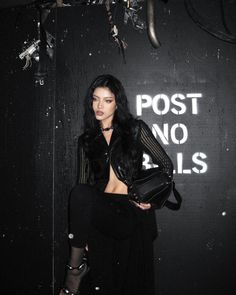 a woman standing in front of a black wall with writing on the wall behind her