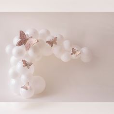 a bunch of white balloons with some butterflies on them and one balloon in the shape of a letter