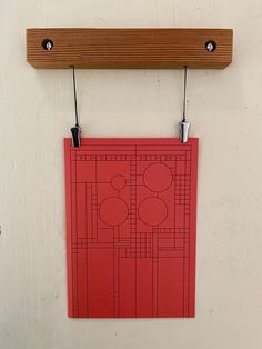 a red piece of paper hanging on a wall next to a wooden peg board with hooks