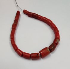 a red beaded necklace on a white surface