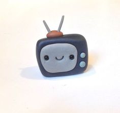 a toy tv with a smile on it's face sitting on a white surface