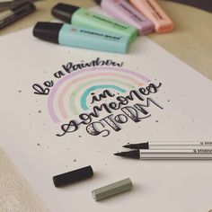 some pens and markers are on top of a piece of paper that says be a rainbow