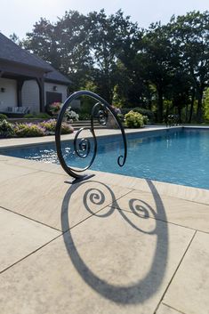 the shadow of an object is cast on the ground next to a swimming pool