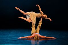 two people are performing on the floor with their hands in the air and one person is upside down