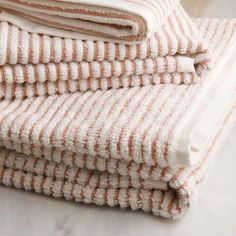 stack of towels folded on top of each other in white and orange stripes, sitting on a marble surface