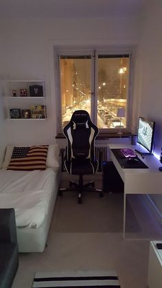 a room with a bed, desk and computer