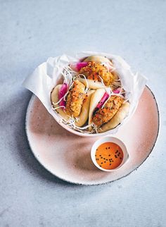 a plate with some food on it next to a small bowl of dipping sauces