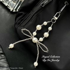 a black purse with white pearls and a chain attached to the clasps on it