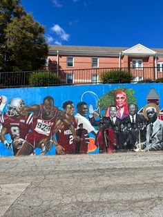 a large mural painted on the side of a building in front of a blue fence