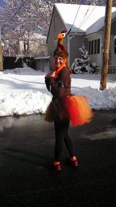 a woman is dressed up in an orange tutu and headband while walking down the street