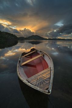 a boat sitting on top of a lake under a cloudy sky