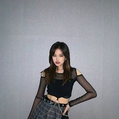 a young woman in a black top and plaid skirt posing for the camera with her hands on her hips