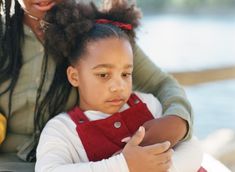 a woman holding a child in her arms and looking at something off to the side