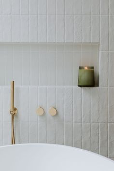 a white bath tub sitting next to a wall mounted candle