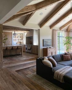 a living room filled with furniture and wooden beams