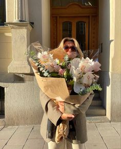 a woman holding flowers in front of a building