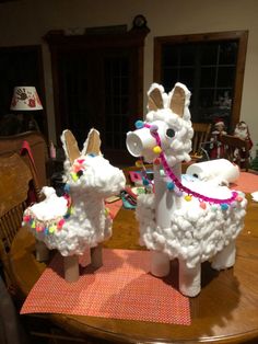 two paper mache llamas sitting on top of a wooden table