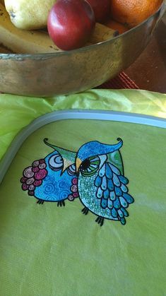 an owl appliqued on the side of a green cloth with fruit in the background