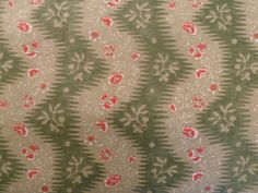 an upholstered fabric with red flowers and green leaves on it's side