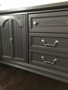 a gray dresser with ornate handles and drawers