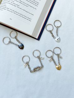 five key chains are laying next to an open book