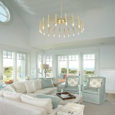 a living room filled with lots of white furniture and windows covered in light blue curtains