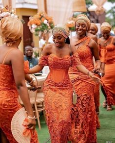 two women in orange dresses standing next to each other