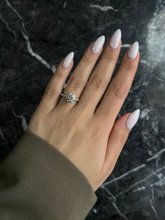 a woman's hand with white manies and a diamond ring on her finger