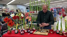 a man standing in front of a table filled with vases and flowers on display