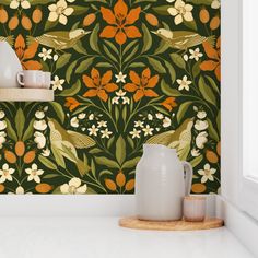 an orange and green floral wallpaper with white vases on the counter next to it