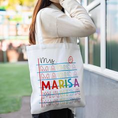 a woman holding a white tote bag with the words marsa on it