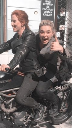 two women riding on the back of a motorcycle