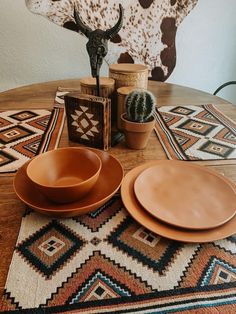 a wooden table topped with two brown plates and three small cactuses next to each other