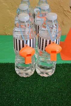 two water bottles with orange lids and straws in them on top of green grass