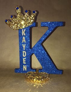 the letter k is made up of glitter and has a crown on top of it