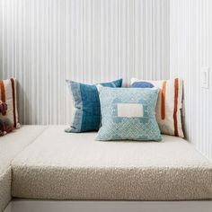 a white couch with pillows on top of it and a stuffed bear sitting next to it